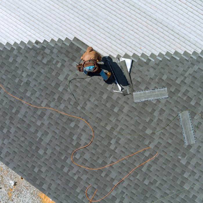 Aerial top view a asphalt shingles installation on the roof roofer is nailing asphalt shingles to roofing construction