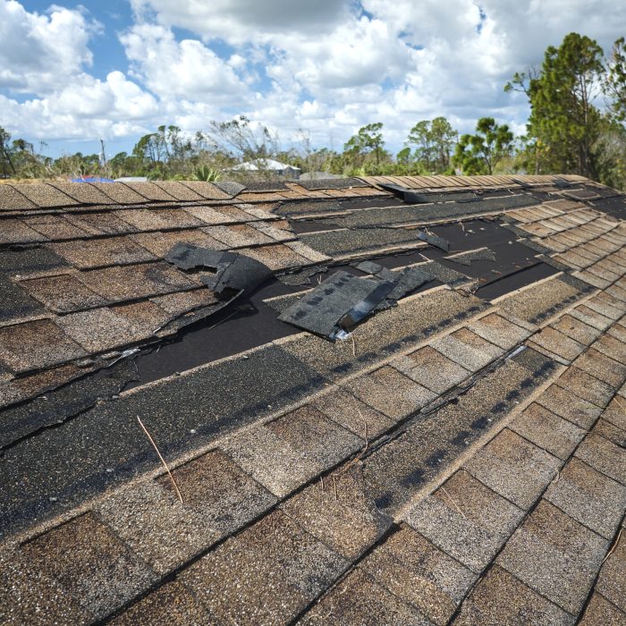 Damaged house roof with missing shingles after hurricane Ian in Florida. Consequences of natural disaster.